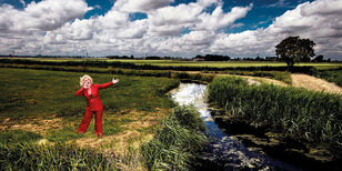 Karin Bloemen Karin staat zingend in een weiland. Ze draagt een rood pak.