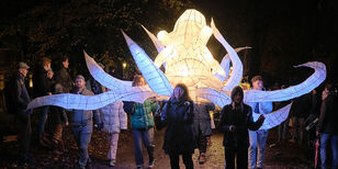 Een groep mensen draagt een grote, lichtgevende octopus tijdens de Sint Maartenparade.