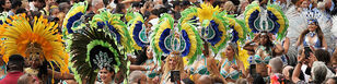 Een groep danseressen met veren hoofdtooien van wel een meter hoog in de Zomercarnaval parade.